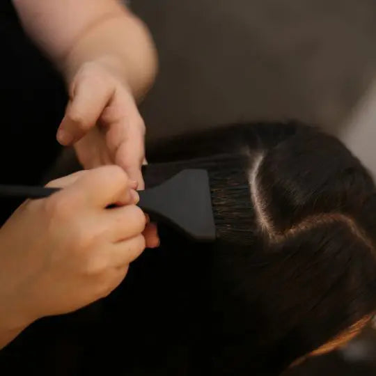 Brush applying glaze through a section of hair