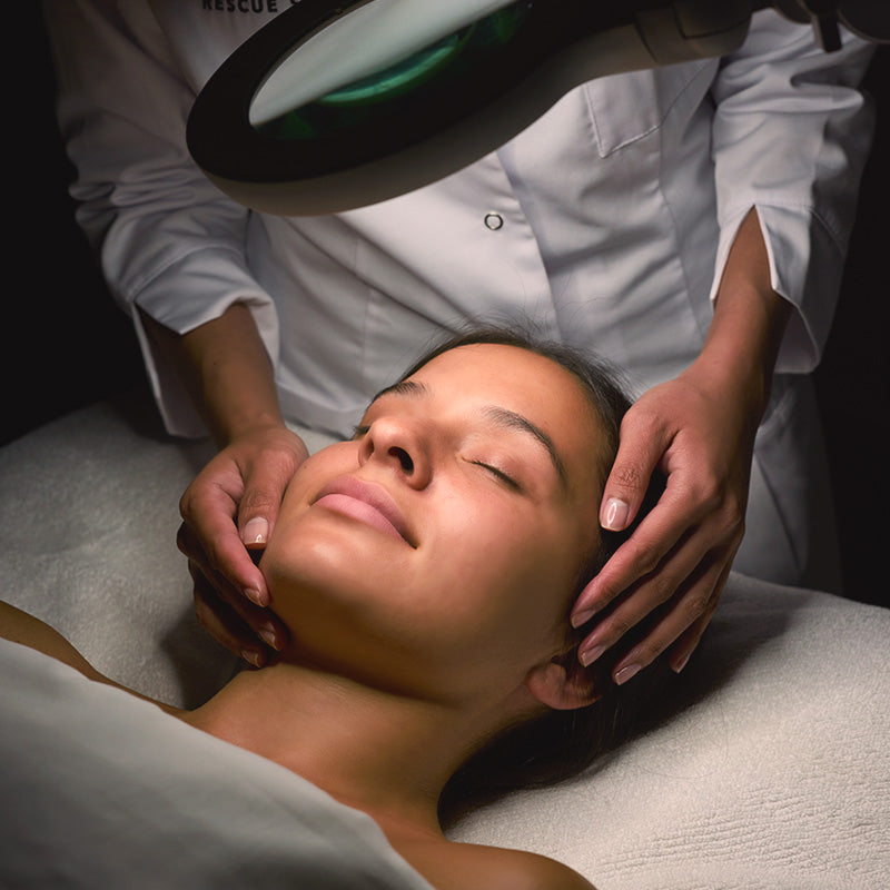 Esthetician examining skin under a magnifying lamp